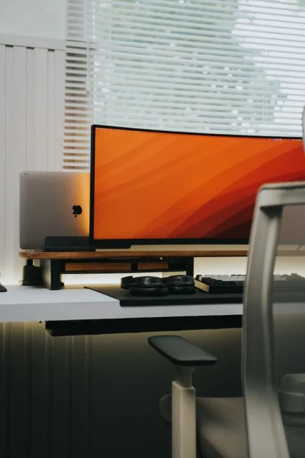 A minimalist desk setup featuring dual monitors, keyboard, mouse, and notebook for productivity.